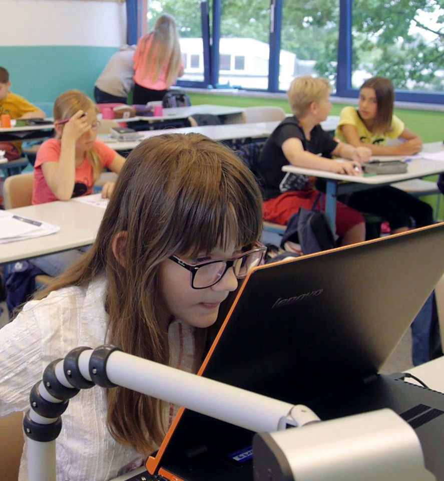 Eine Schülerin sitzt im Klassenraum vor ihrem Laptop und ihrer Tafelbildkamera.