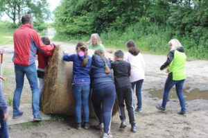 Mehrere Schüler*innen rollen einen Rundballen.