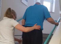 Beim Treppensteigen ist eine gute Koordination von Unterarmgehstützen und Beinen gefordert. Hier gebe ich detaillierte Anweisungen zum Bewegungsablauf, damit der Patient schon bald gefahrlos die Treppen hoch und hinunter steigen kann.