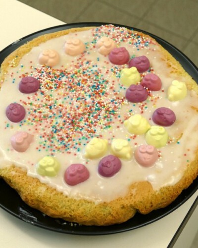 Selbstgebackener Kuchen mit weißer Glasur, bunten Streuseln und farbigen obstförmigen Zuckerstücken