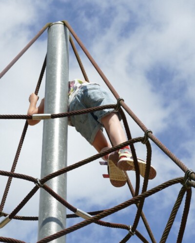 Ein Kind klettert im Klettertau unter blauem Himmel