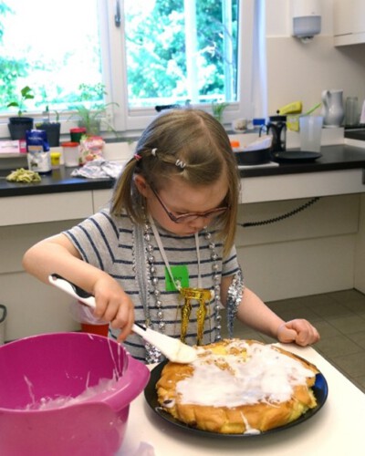 Ein Mädchen bestreicht in der Kurshaus-Küche einen Kuchen mit Zuckerguss